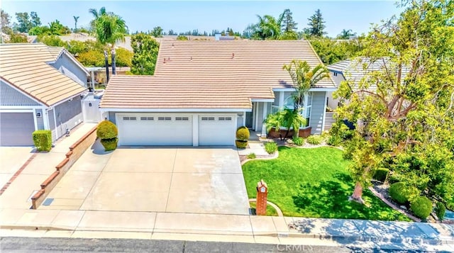 view of front of home featuring driveway, a tile roof, an attached garage, and a front lawn