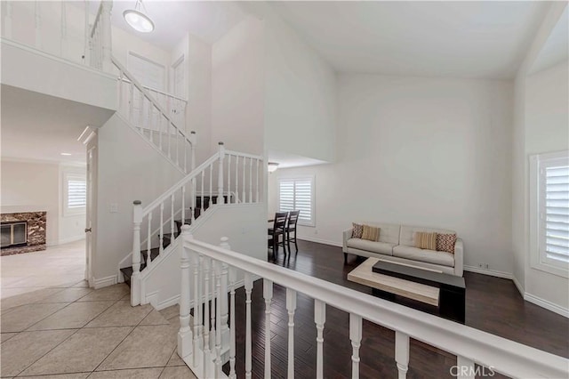 stairway with a towering ceiling, baseboards, tile patterned flooring, and a glass covered fireplace
