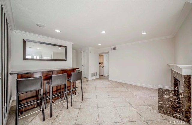 tiled dining area with a dry bar, ornamental molding, baseboards, recessed lighting, and a fireplace