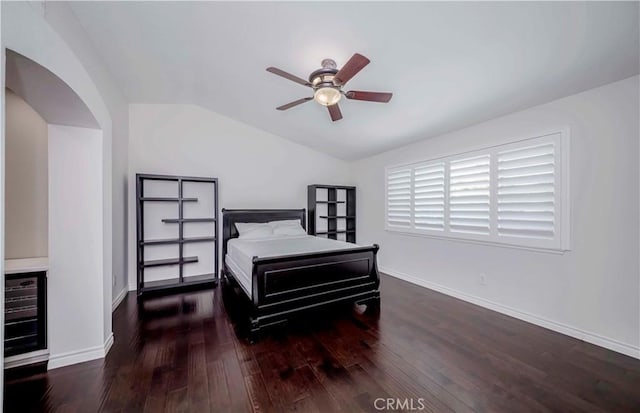 bedroom featuring lofted ceiling, wood-type flooring, baseboards, a ceiling fan, and arched walkways