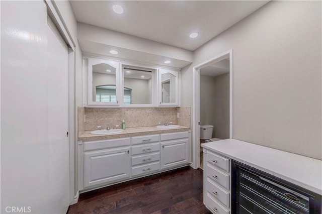 bathroom featuring hardwood / wood-style floors, toilet, decorative backsplash, double vanity, and recessed lighting