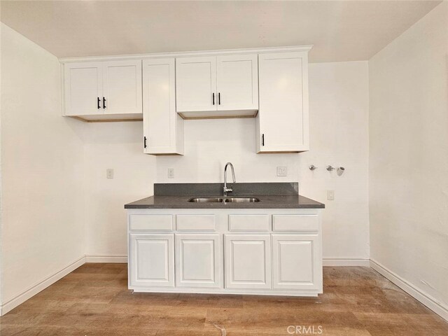 1335 W 11th St, Pomona, CA 91766 - kitchen featuring a sink, white cabinets, light wood-type flooring, and dark countertops