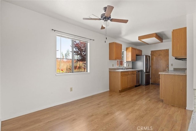 6383 Harvey Rd, Paradise, CA 95969 - kitchen with appliances with stainless steel finishes, light countertops, brown cabinetry, light wood finished floors, and a sink