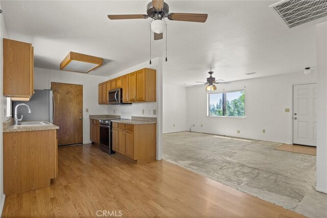 6383 Harvey Rd, Paradise, CA 95969 - kitchen featuring appliances with stainless steel finishes, a ceiling fan, brown cabinets, open floor plan, and light wood-style flooring