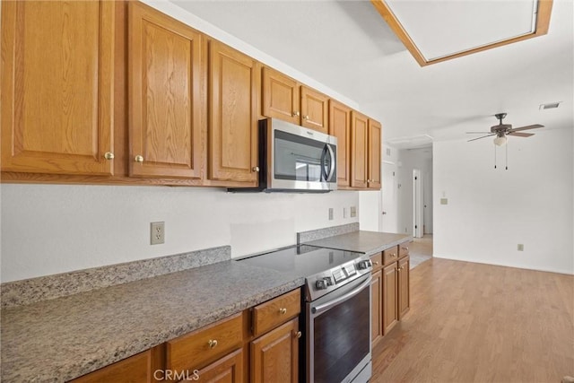 6383 Harvey Rd, Paradise, CA 95969 - kitchen featuring stainless steel appliances, light wood finished floors, ceiling fan, and brown cabinetry