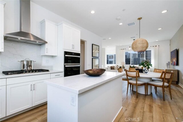 73 Culture, Irvine, CA 92618 - kitchen with wall chimney exhaust hood, light wood-style flooring, a kitchen island, decorative backsplash, and white cabinets