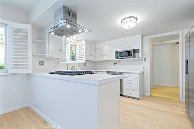 622 S Halcyon Rd, Arroyo Grande, CA 93420 - kitchen featuring island range hood, appliances with stainless steel finishes, a peninsula, light wood finished floors, and white cabinetry