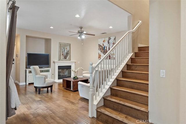 15561 Jasmine Pl, Tustin, CA 92782 - stairs with wood finished floors, ceiling fan, recessed lighting, a glass covered fireplace, and baseboards
