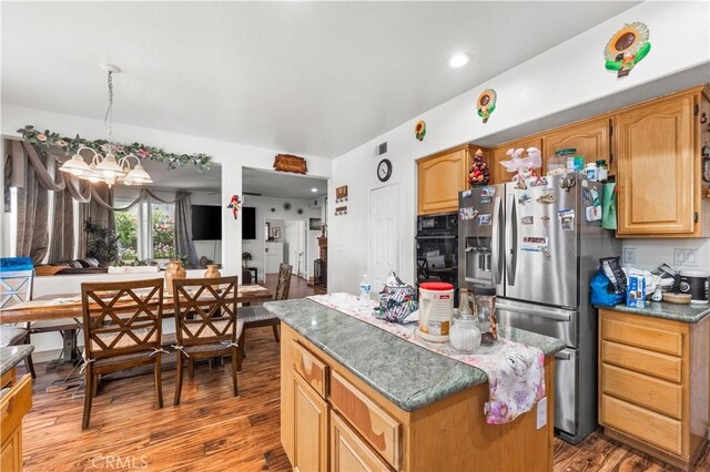3410 Genoa Pl, Palmdale, CA 93551 - kitchen with stainless steel fridge with ice dispenser, wood finished floors, a chandelier, a center island, and black oven
