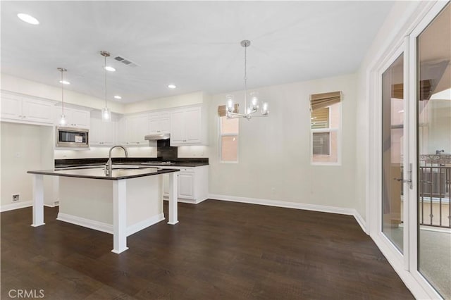 20304 Estuary Ln, Newport Beach, CA 92660 - kitchen with stainless steel microwave, dark countertops, under cabinet range hood, white cabinets, and recessed lighting