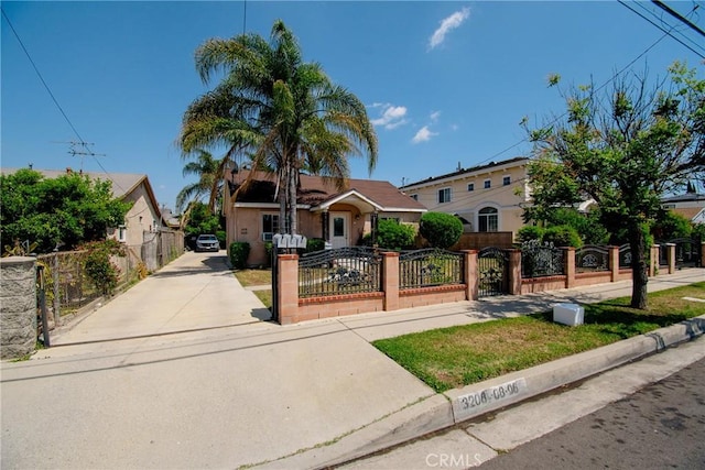 view of front of home with concrete driveway, a fenced front yard, a gate, and stucco siding
