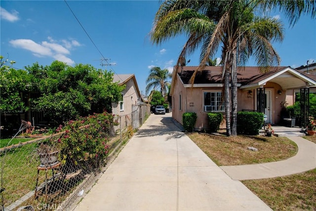 view of front of property featuring stucco siding, driveway, and fence