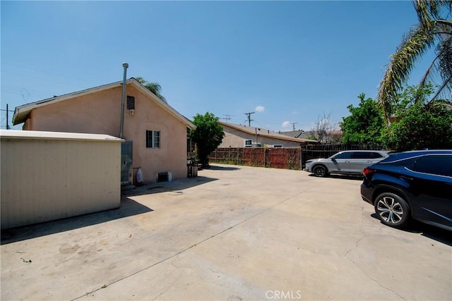 view of side of property with fence and stucco siding