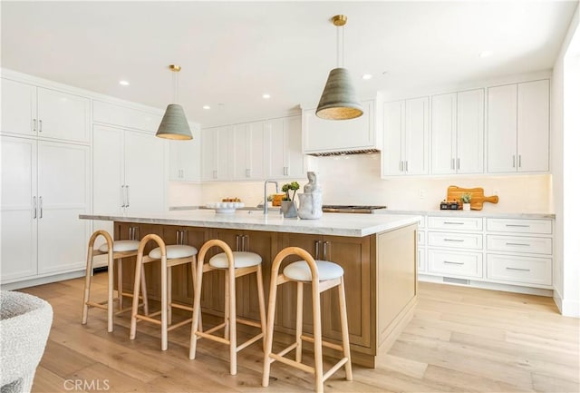 1759 Glenneyre St, Laguna Beach, CA 92651 - kitchen featuring a kitchen island with sink, white cabinets, a breakfast bar area, light wood-style flooring, and recessed lighting