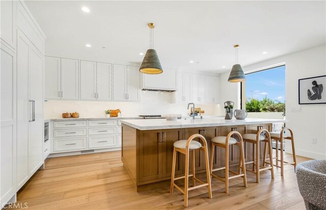 1759 Glenneyre St, Laguna Beach, CA 92651 - kitchen featuring light wood finished floors, light countertops, white cabinetry, an island with sink, and recessed lighting