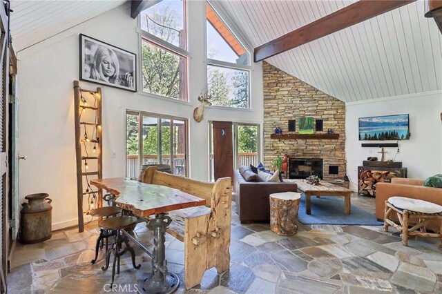 385 Iris Dr, Twin Peaks, CA 92391 - dining room featuring stone tile flooring, high vaulted ceiling, a stone fireplace, beamed ceiling, and baseboards