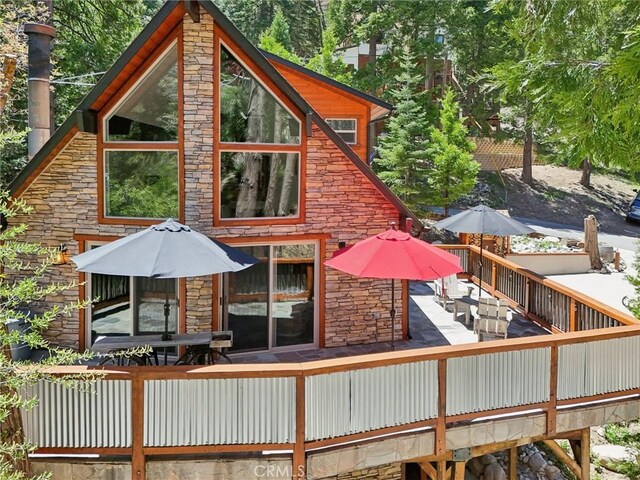 385 Iris Dr, Twin Peaks, CA 92391 - back of property with stone siding, a deck, and outdoor dining area