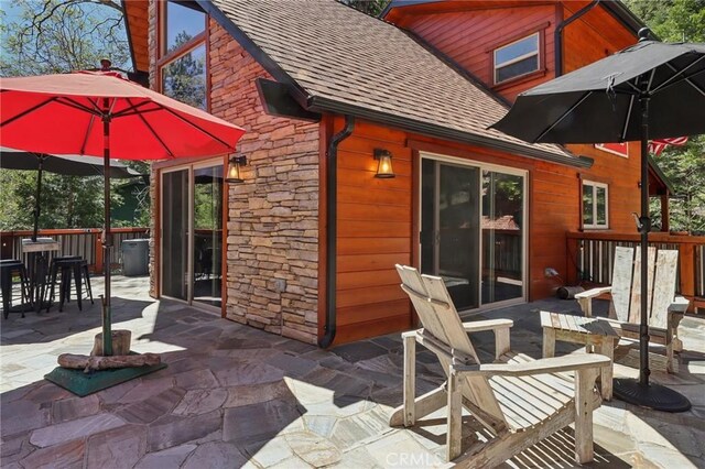 385 Iris Dr, Twin Peaks, CA 92391 - rear view of house with stone siding, a shingled roof, and a patio