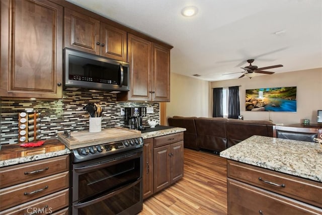 12427 Stardell Ln, Yucaipa, CA 92399 - kitchen featuring stainless steel microwave, double oven range, open floor plan, light wood-type flooring, and ceiling fan