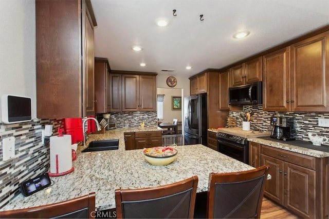 12427 Stardell Ln, Yucaipa, CA 92399 - kitchen with black appliances, a sink, tasteful backsplash, a peninsula, and a kitchen breakfast bar