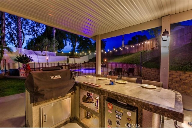 12427 Stardell Ln, Yucaipa, CA 92399 - patio at twilight with a fenced backyard, exterior kitchen, and grilling area