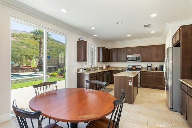 34130 Camelina St, Lake Elsinore, CA 92532 - kitchen with stainless steel appliances, a center island, dark brown cabinets, light tile patterned floors, and crown molding