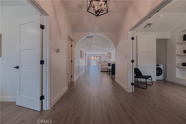 3448 Ferncroft Rd, Los Angeles, CA 90039 - hall with arched walkways, wood finished floors, washer / dryer, a chandelier, and baseboards