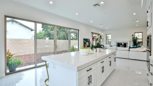 kitchen featuring recessed lighting, white cabinetry, a center island, light countertops, and open floor plan