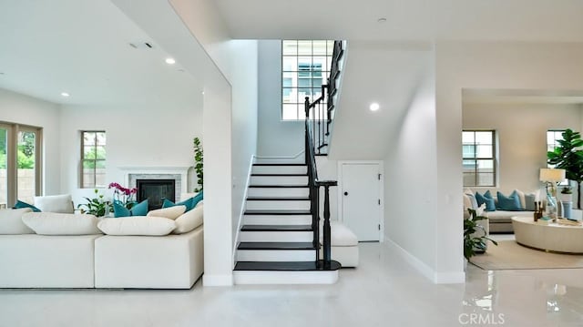 stairway with baseboards, healthy amount of natural light, recessed lighting, and a glass covered fireplace