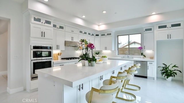 kitchen featuring stainless steel appliances, white cabinets, a center island, light countertops, and recessed lighting