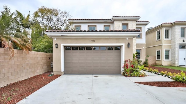 mediterranean / spanish home featuring stucco siding, fence, concrete driveway, a garage, and a tile roof