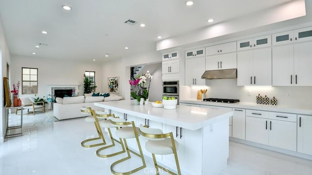 kitchen featuring under cabinet range hood, a kitchen island, black gas stovetop, recessed lighting, and white cabinetry