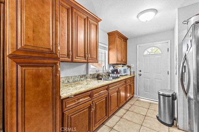 9502 Westminster Ave, Garden Grove, CA 92844 - kitchen featuring a sink, white microwave, freestanding refrigerator, light tile patterned flooring, and brown cabinetry