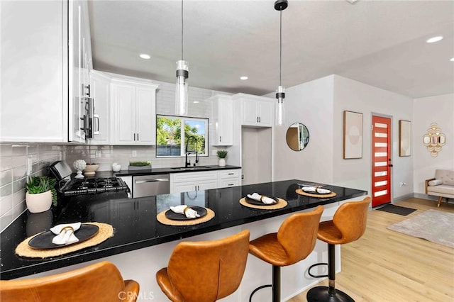 3017 Date St, Riverside, CA 92507 - kitchen with a peninsula, appliances with stainless steel finishes, light wood finished floors, dark countertops, and decorative backsplash