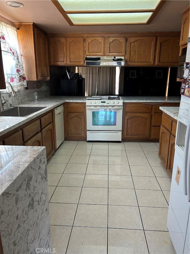 7218 Dalscote St, Hesperia, CA 92345 - kitchen with white appliances, under cabinet range hood, brown cabinets, and light tile patterned flooring