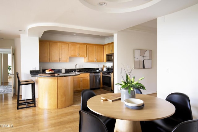 12603 Moorpark St Unit 303, Studio City, CA 91604 - kitchen featuring stainless steel appliances, dark countertops, a peninsula, ornamental molding, and light wood-style flooring