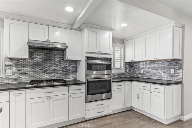 15439 Studebaker Rd, Norwalk, CA 90650 - kitchen featuring under cabinet range hood, appliances with stainless steel finishes, dark countertops, white cabinetry, and light wood-type flooring