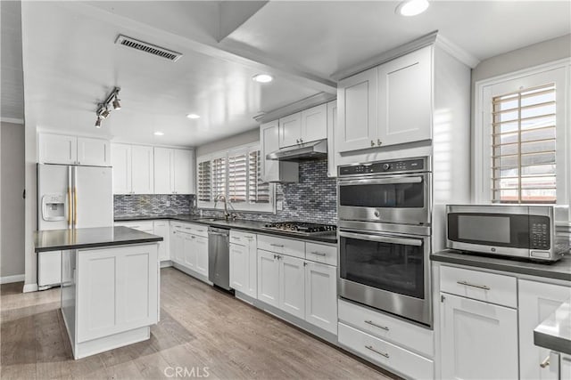 15439 Studebaker Rd, Norwalk, CA 90650 - kitchen with stainless steel appliances, a sink, dark countertops, white cabinets, and decorative backsplash