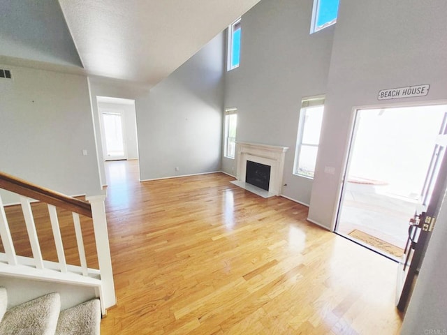 7 Via Encanto, Rancho Santa Margarita, CA 92688 - unfurnished living room with light wood-style flooring, stairway, a fireplace, and a high ceiling