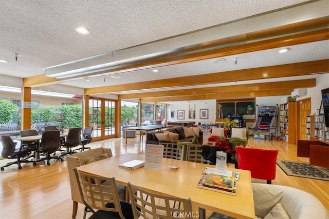 dining area with a textured ceiling, wood finished floors, recessed lighting, a wall mounted AC, and french doors