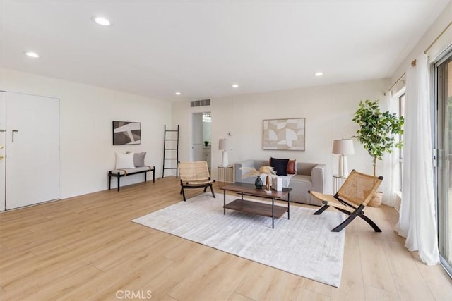 living room with light wood-type flooring and recessed lighting
