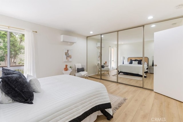 bedroom featuring an AC wall unit, light wood-style floors, recessed lighting, and a closet