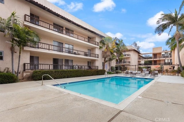community pool with fence and a patio area