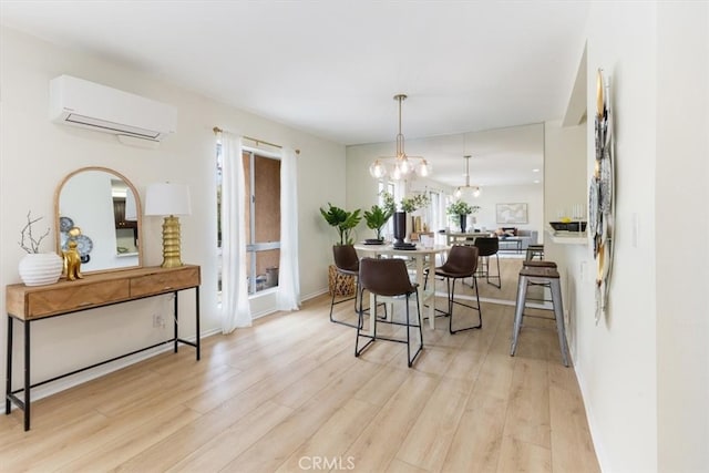 dining room with a wall mounted AC, light wood finished floors, a chandelier, and baseboards