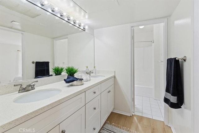 full bathroom featuring double vanity, wood finished floors, and baseboards