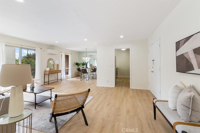 living area with an AC wall unit, light wood-style floors, a chandelier, recessed lighting, and baseboards