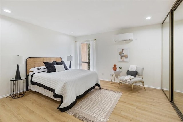bedroom with a wall unit AC, light wood finished floors, recessed lighting, and baseboards