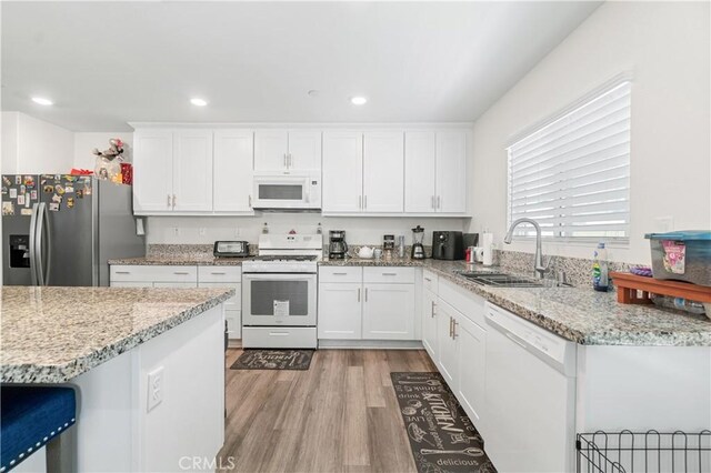 2044 E Lingard St, Lancaster, CA 93535 - kitchen with white appliances, a sink, white cabinetry, light wood-type flooring, and light stone countertops