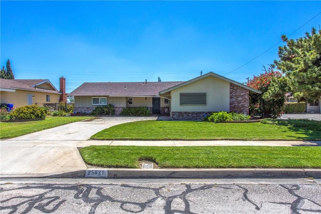 25821 28th St, San Bernardino, CA 92404 - ranch-style home with stone siding, a front yard, driveway, and stucco siding