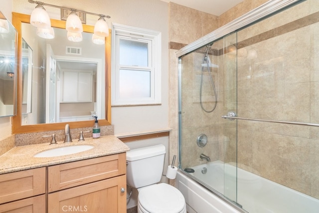 bathroom with vanity, shower / bath combination with glass door, and toilet